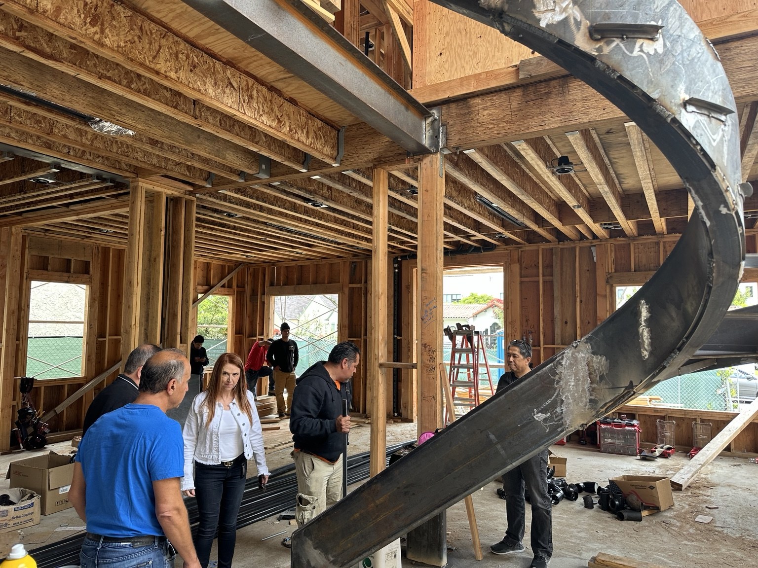 On-site discussion beside the curved steel staircase during framing